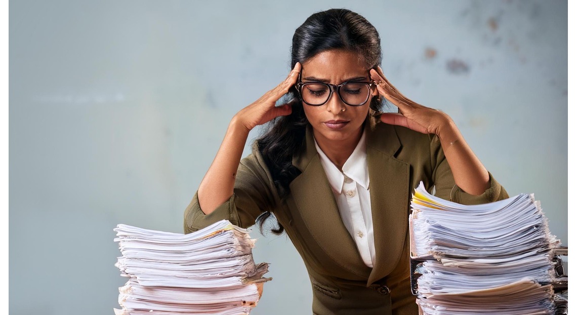 Stressed Teacher checking huge pile of copies